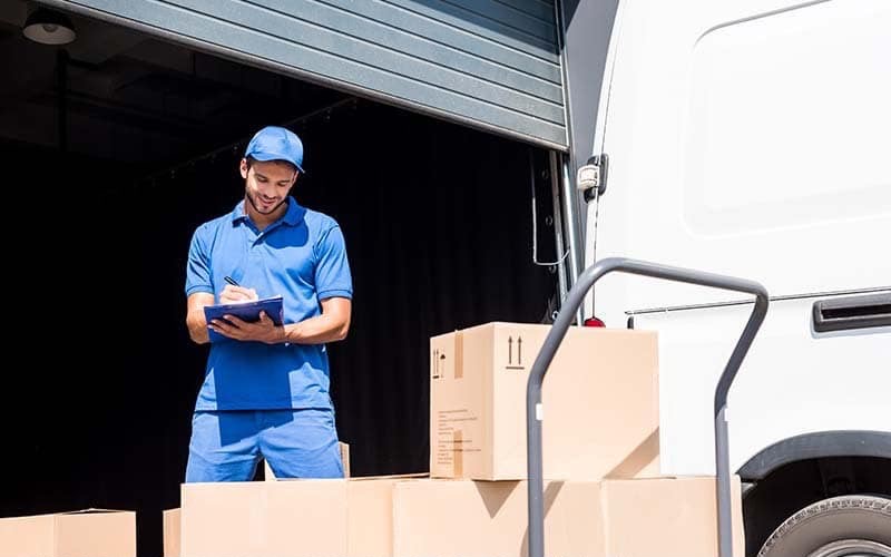 Courier completing delivery paperwork beside boxes